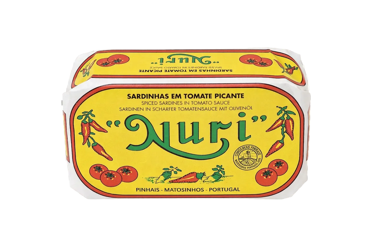 A tin of Nuri Spiced Sardines in Tomato Sauce, featuring a bright yellow label with green 'Nuri' lettering and illustrations of red tomatoes and chili peppers, shown on a transparent checkerboard background.