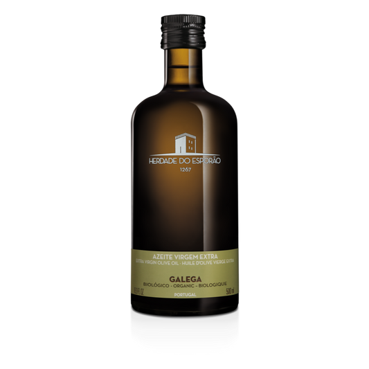 A bottle of Herdade do Esporão organic virgin olive oil with a label indicating it is Galega variety. The bottle is dark tinted with a black cap, and the label is primarily in white and green colors.